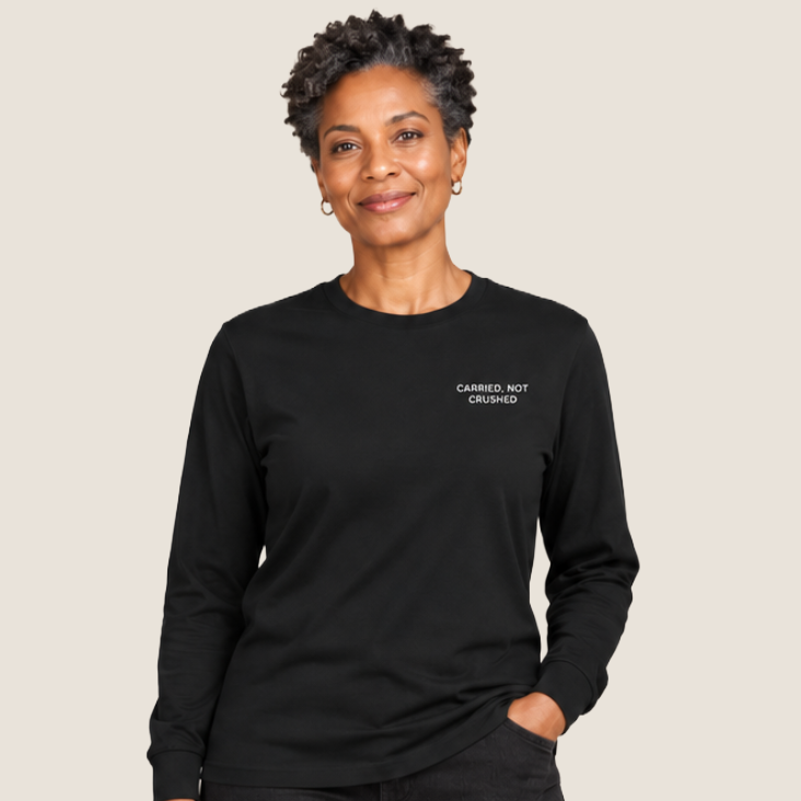 Woman in black pants and a black long sleeve t-shirt that say CARRIED, NOT CRUSHED on the upper left chest.