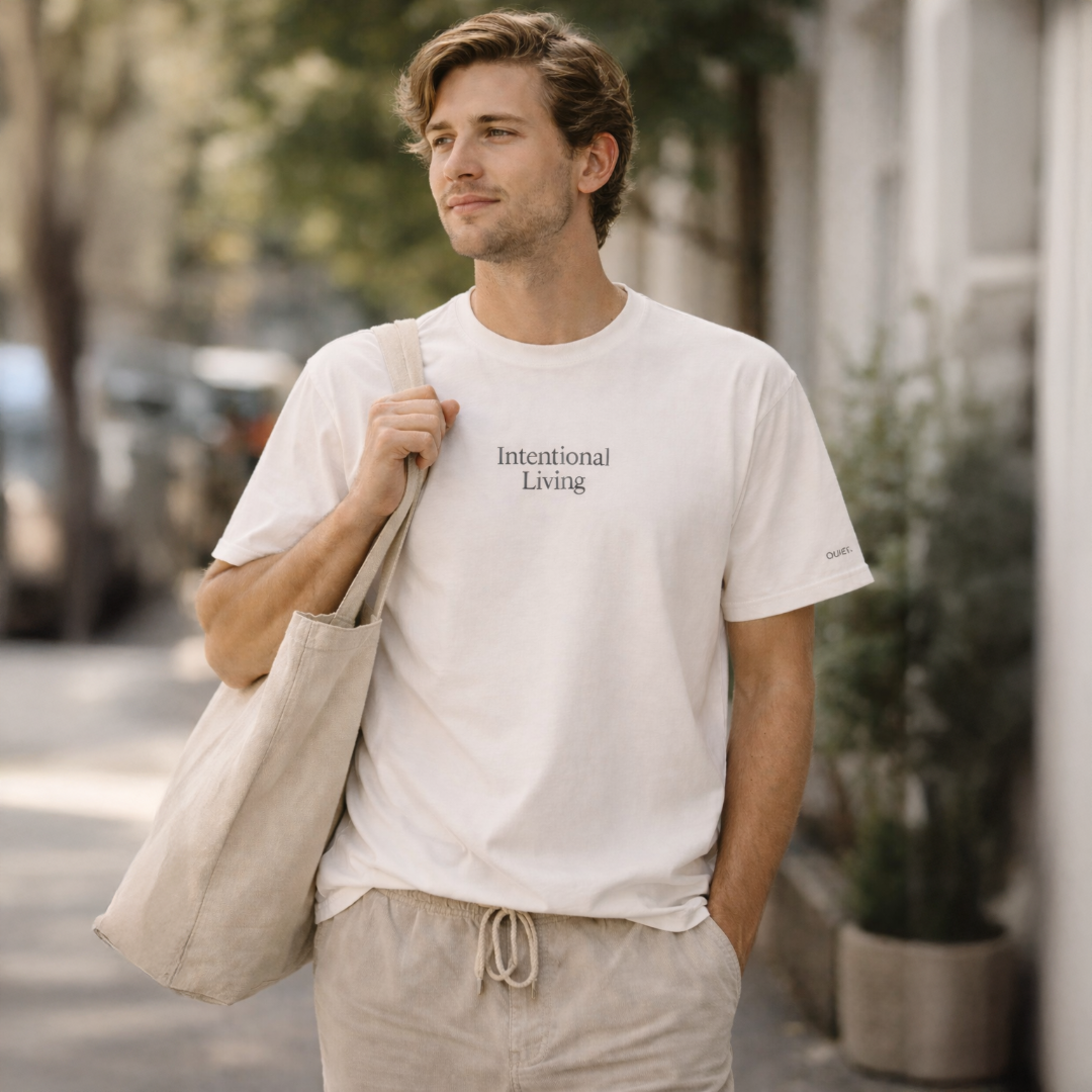 Man with a cream t-shirt that says Intentional Living carrying a tote bag and walking down a sidewalk.