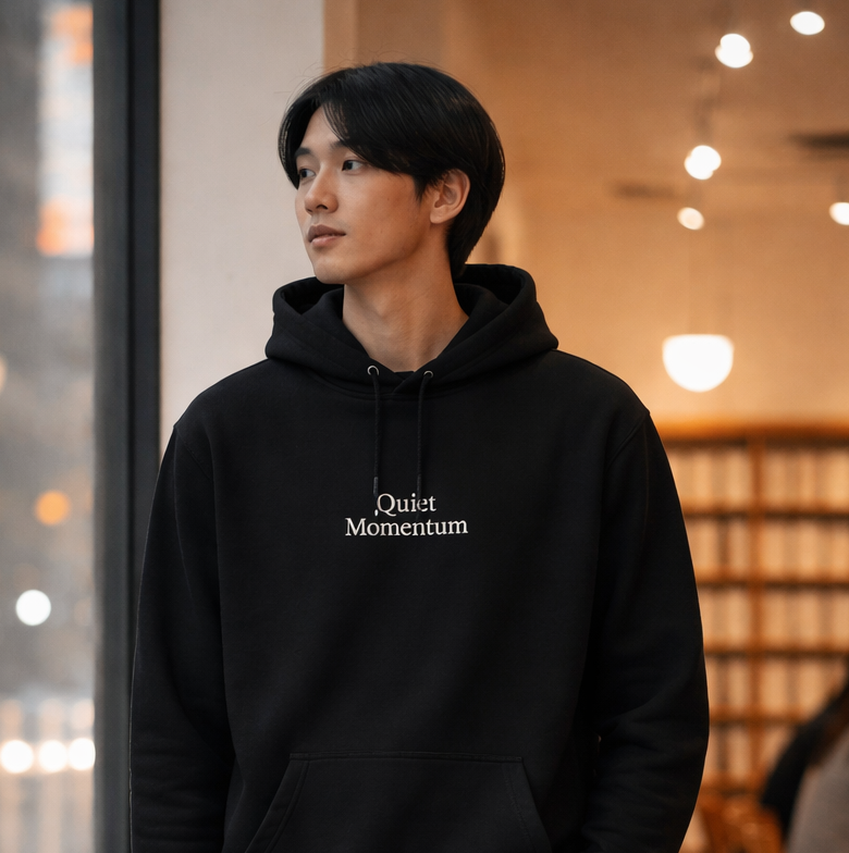 Person wearing a black hoodie with text in a casual setting