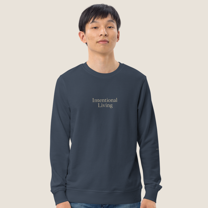 Male wearing a navy crewneck sweatshirt with Intentional Living on the chest.