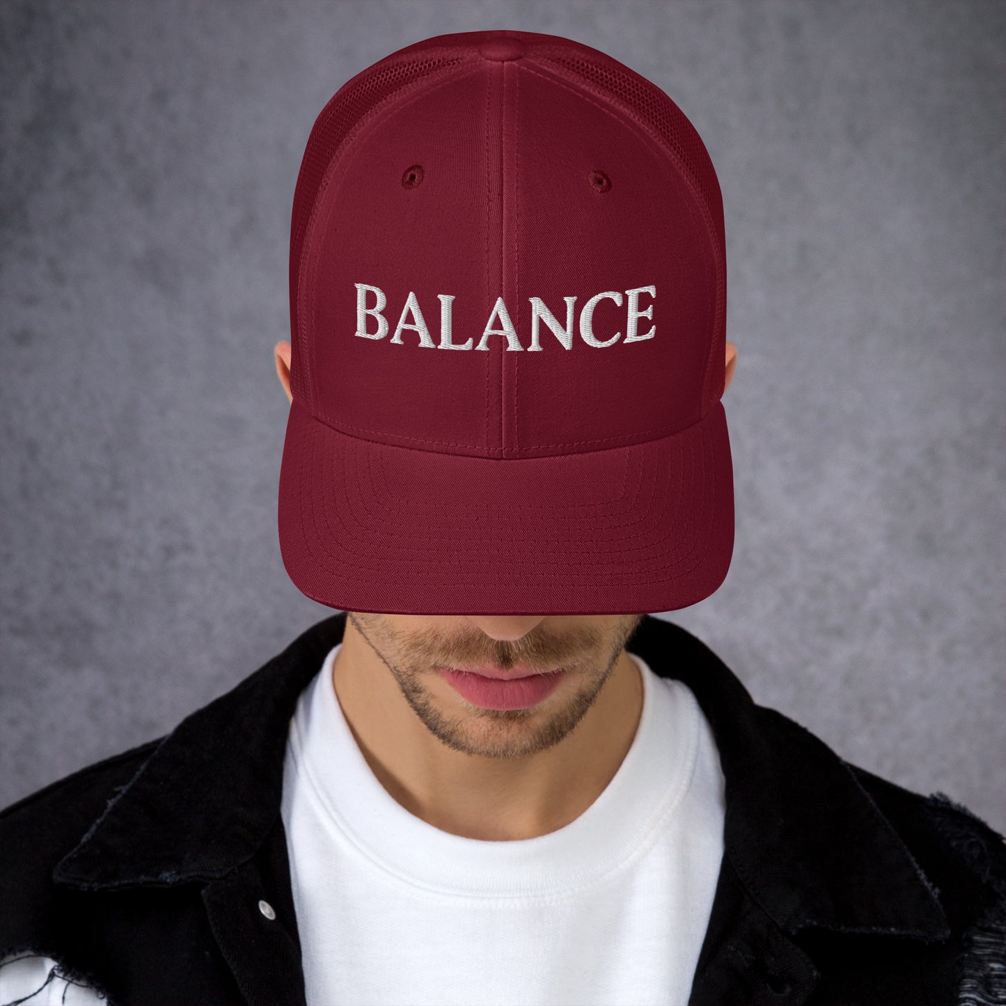 Maroon cap with 'BALANCE' text worn by a person against a gray background