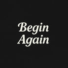 Black sweatshirt with 'Begin Again' text on a beige background