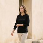 Woman wearing a black sweatshirt with 'BREATHE' text, walking outdoors.
