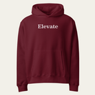 A maroon pullover hoodie with the word 'Elevate' printed in white serif font across the chest, displayed on a light off-white background.