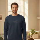 Man wearing a navy blue sweatshirt with 'Intentional Living' text in a living room.