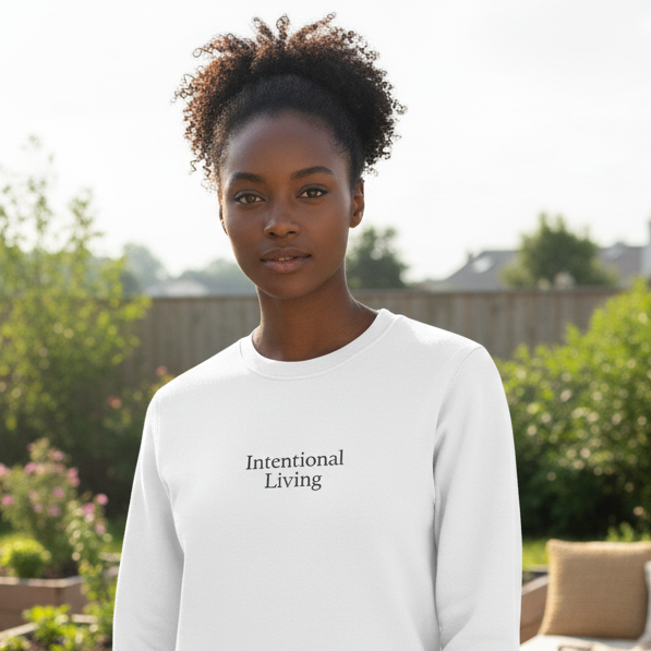 Person wearing a white sweatshirt with 'Intentional Living' text in a garden setting