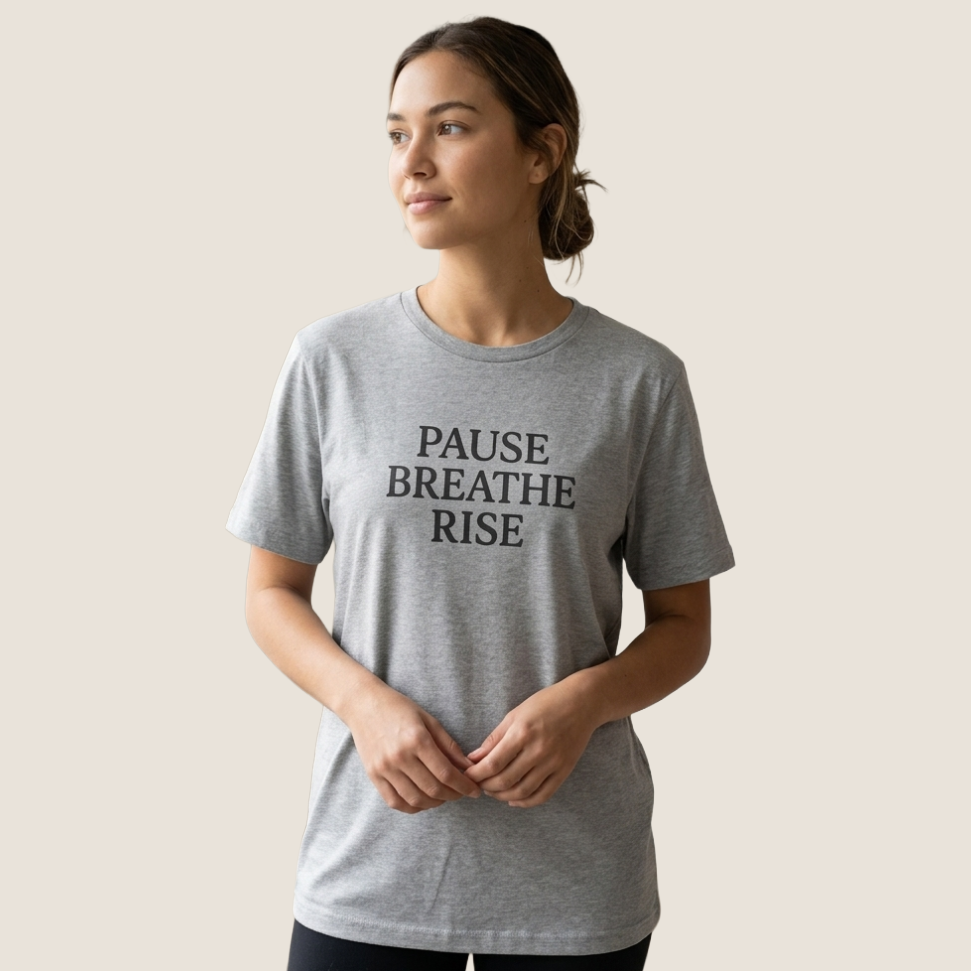 Woman wearing a gray t-shirt with "PAUSE BREATHE RISE" on the chest.