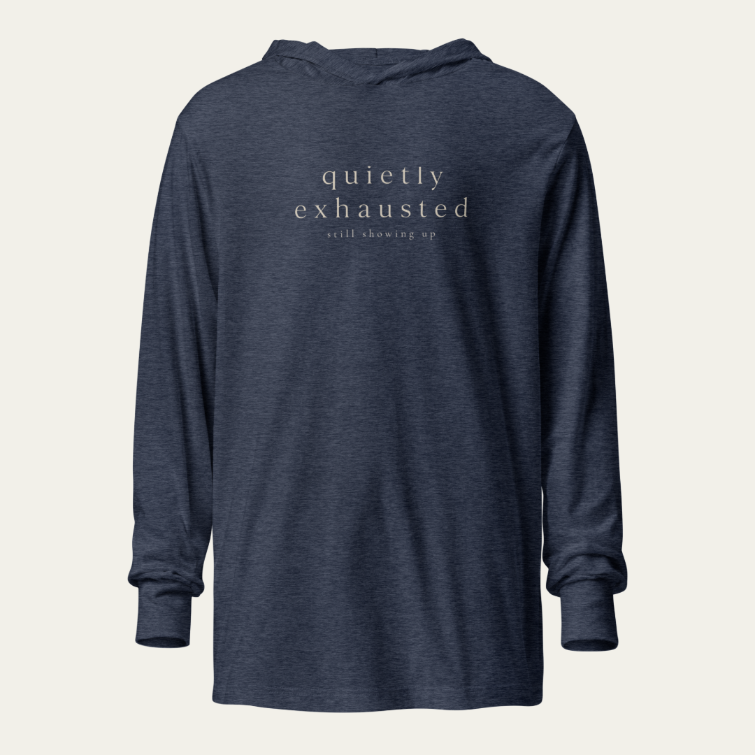 Navy blue hooded long sleeve tee with "quietly exhausted" and "still showing up" on the chest