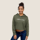 Woman wearing an olive cropped hoodie with "Still Becoming" text across text on a beige background.
