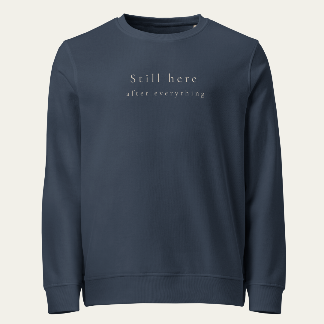 French navy crewneck sweatshirt with Still here after everything on upper center chest.