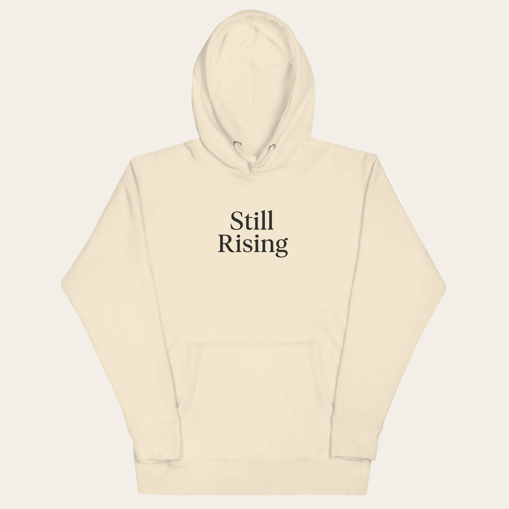 Beige hoodie with 'Still Rising' text on a white background