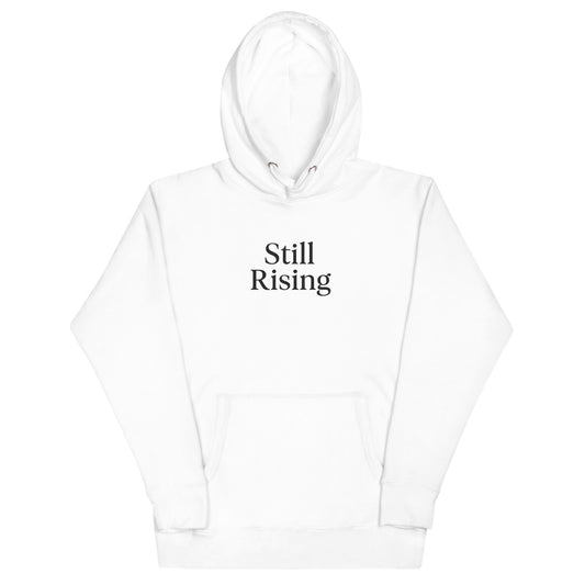 White hoodie with 'Still Rising' text on a white background