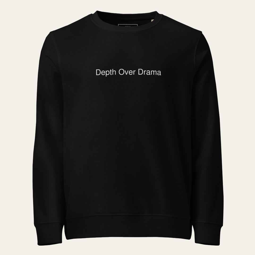 A black crewneck sweatshirt with the phrase 'Depth Over Drama' printed in white sans-serif text across the chest, displayed on a clean, light off-white background.