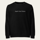 A black crewneck sweatshirt with the phrase 'Depth Over Drama' printed in white sans-serif text across the chest, displayed on a clean, light off-white background.