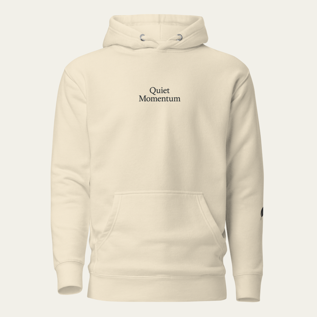 An off-white pullover hoodie with 'Quiet Momentum' printed in black serif text on the chest, displayed on a clean, light off-white background.