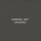 Dark gray hoodie with 'CARRIED, NOT CRUSHED' text on the back against a light beige background