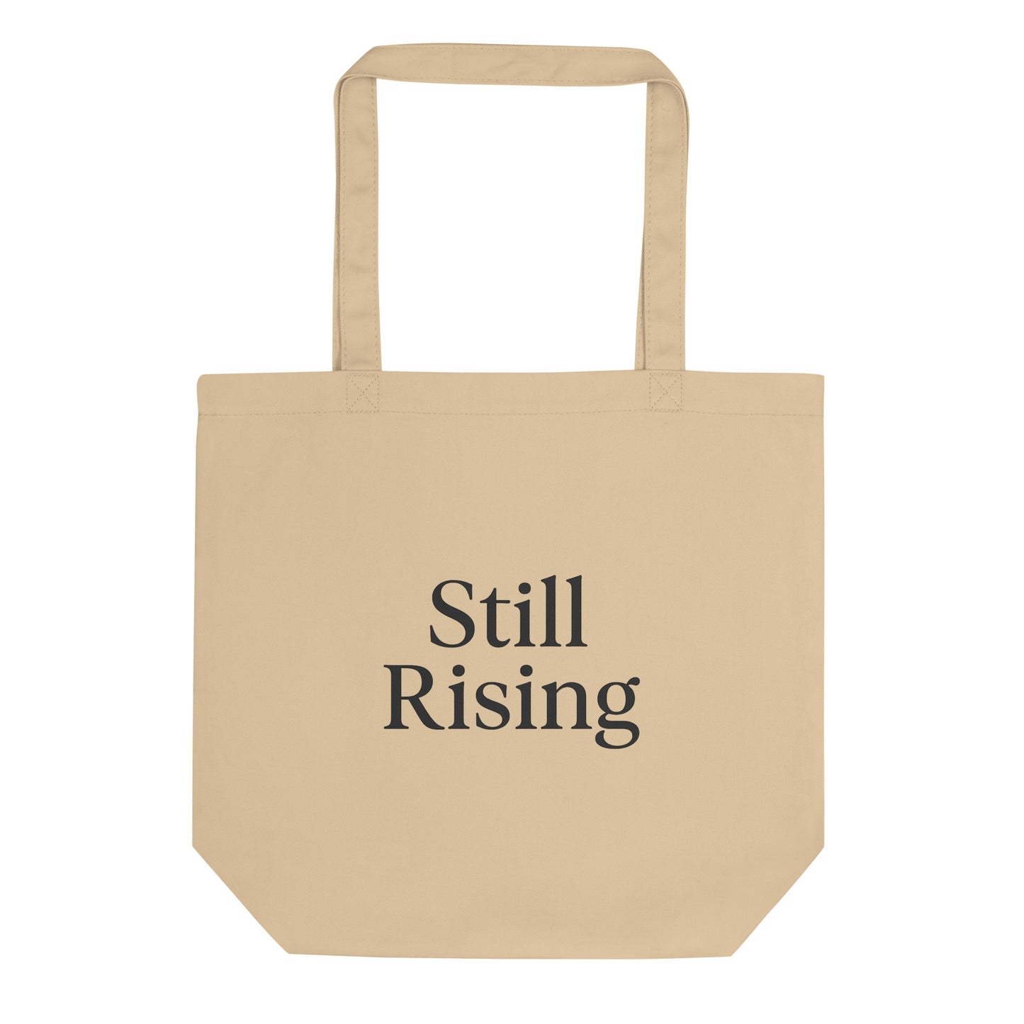 Beige tote bag with 'Still Rising' text on a white background