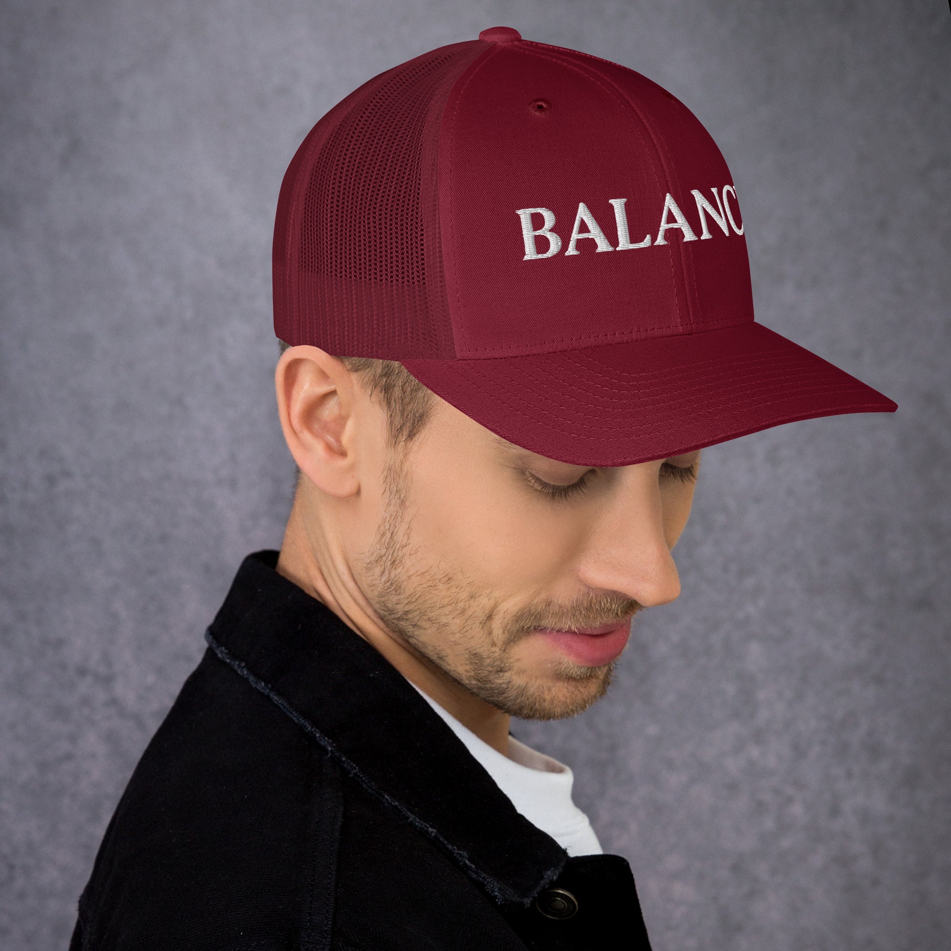 Man wearing a maroon cap with 'BALANCE' text on a gray background