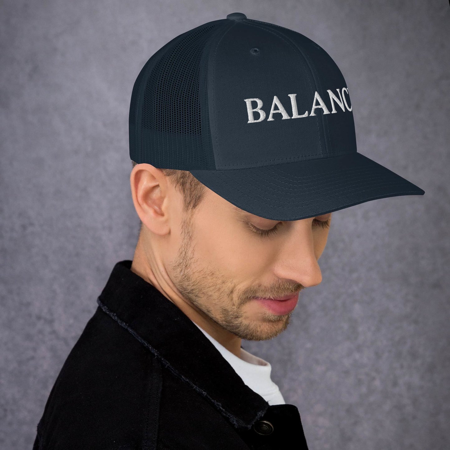 Man wearing a black cap with 'BALANCE' text on a gray background