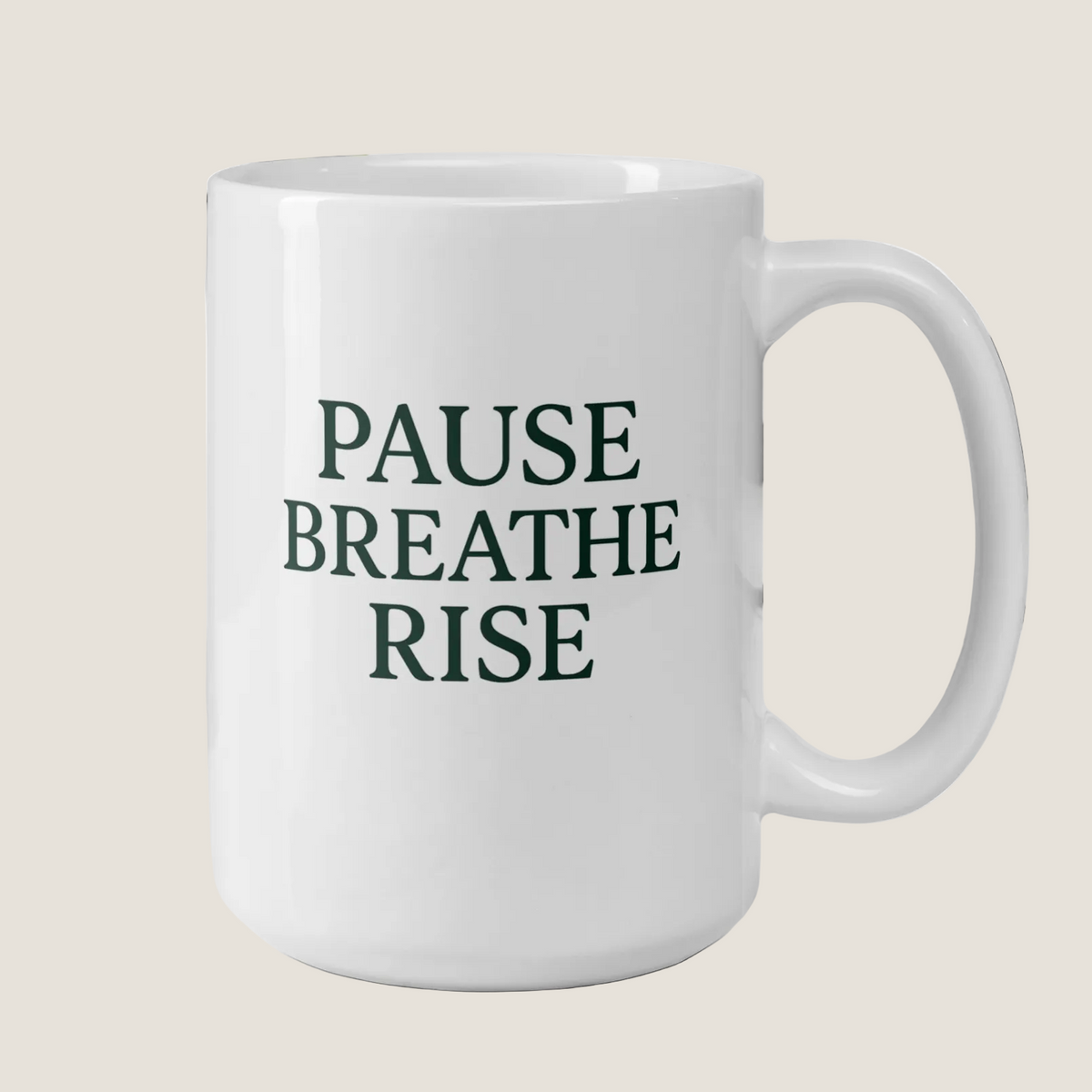 White mug with 'PAUSE BREATHE RISE' text on a desk with a plant and books in the background