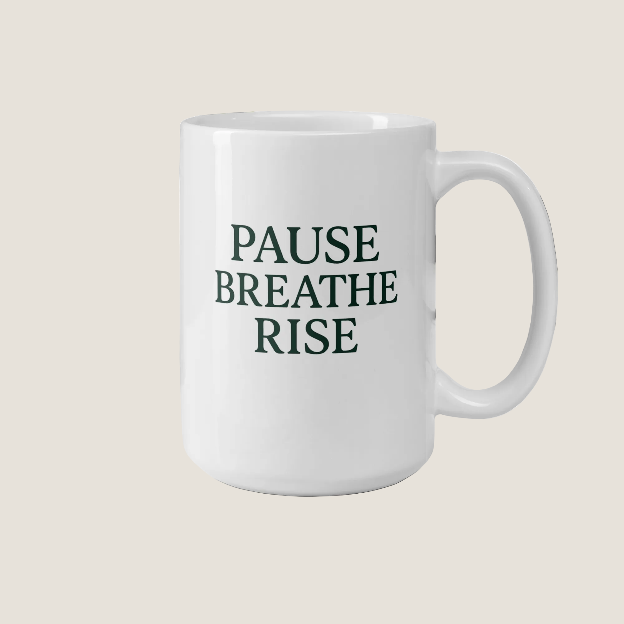 White mug with 'PAUSE BREATHE RISE' text on a desk with a plant and books in the background